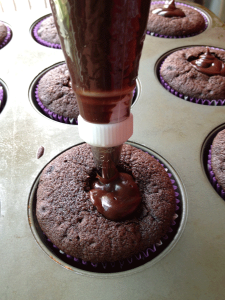 Filling cupcakes with ganache.
